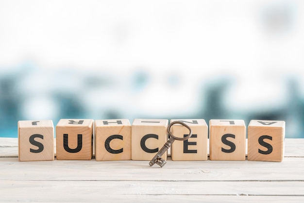 Photo close-up of key with success text on wooden blocks