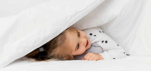 close-up kid hiding under blanket