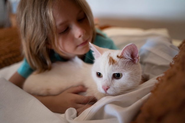 Foto primo piano bambino che tiene in mano un simpatico gatto bianco