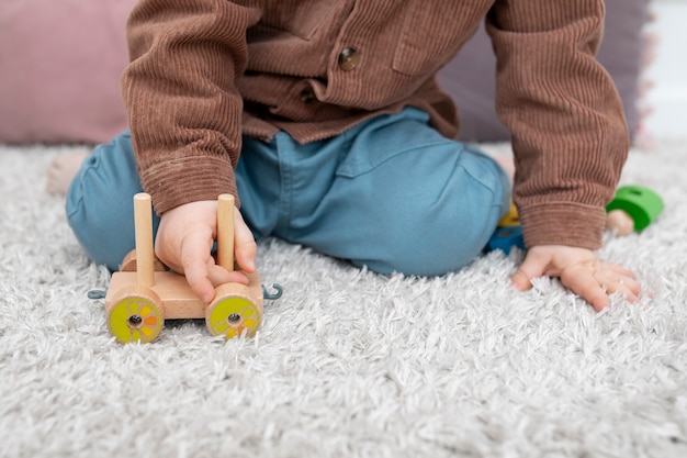 Foto chiuda sul bambino che gioca con l'automobile di legno