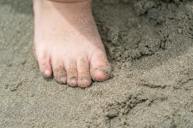 Close up kid's foot and fingers, play and learn at the beach.