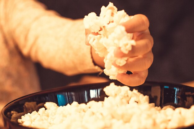 Foto close-up di un bambino che prende popcorn da una ciotola