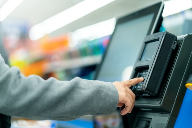 Close-up klant hand betaling teller kassamachine met monitor in supermarkt opslag