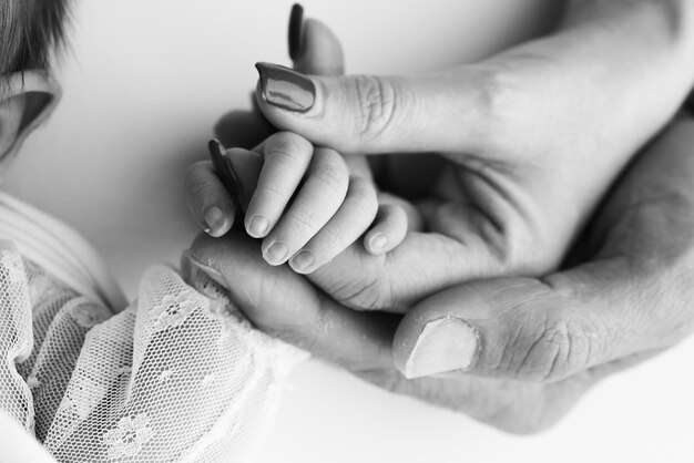 Foto close-up kleine hand van het kind en de handpalm van moeder en vader de pasgeboren baby heeft een stevige greep op de vinger van de ouders na de geboorte een pasgeboren kind houdt vast aan de vingers van de moeder en de vader zwart-wit foto