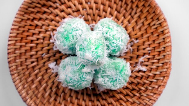 Close up klepon or green sticky rice balls filled with liquid palm sugar in a white background