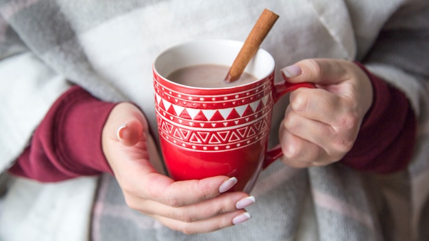 Foto close-up kopje thee, koffie of cacao vrouwelijke handen houden op pastel sjaal achtergrond