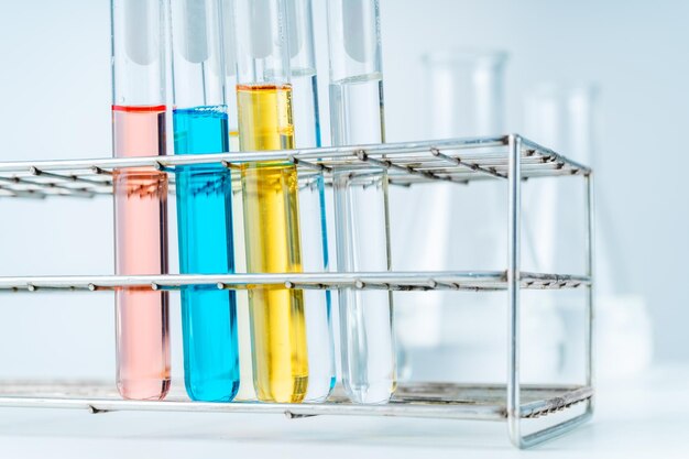 Photo close up of lab test tubes fill with red blue yellow and clear liquid in the tube rack