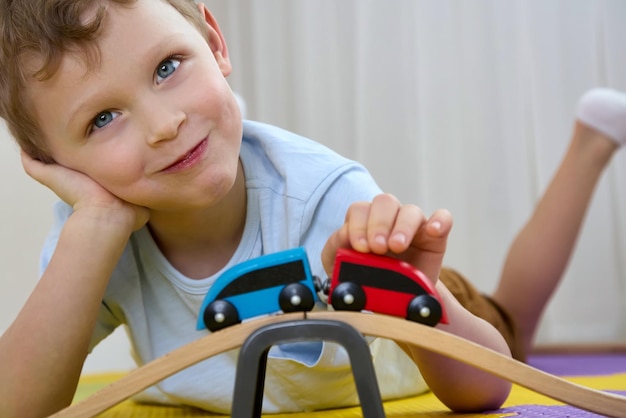 Close-up lachende jongen heeft plezier met het spelen met houten speelgoed op puzzelmatten
