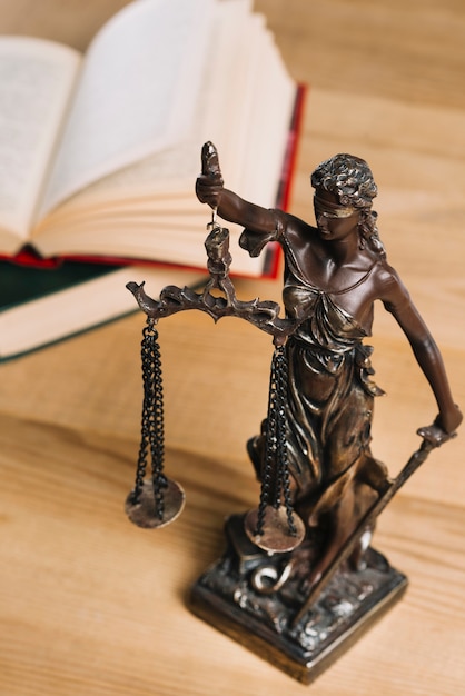 Photo close-up of lady of justice and law books on wooden desk