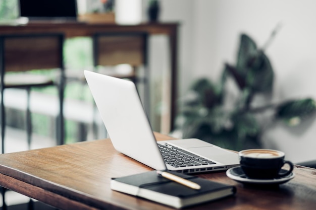 Close-up of laptop by coffee cup on table at home
