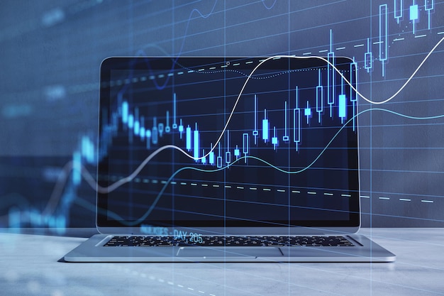 Close up of laptop computer with glowing candlestick forex chart with index on blurry background Trade stock and finance concept Double exposure