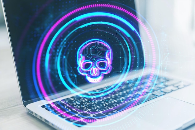 Close up of laptop on desk with creative digital round skull hologram on blurry background Hacking piracy and malware concept Double exposure