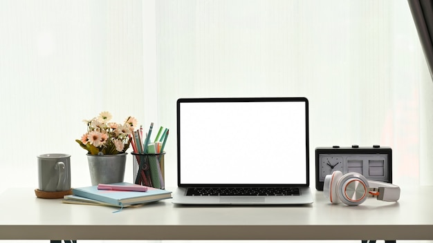 Close up on laptop, head phone, notebook and coffee cup on white table