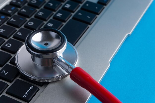 Photo close-up of laptop and stethoscope over blue background