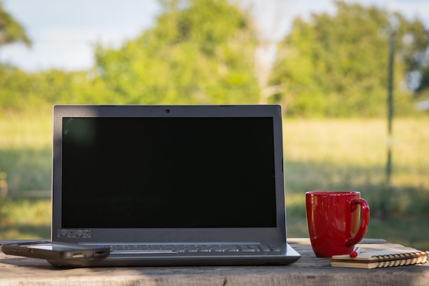 Foto close-up di un portatile con una tazza di caffè sul tavolo all'aperto