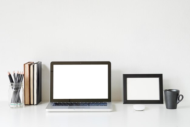 Photo close-up of laptop with equipment on table against white wall