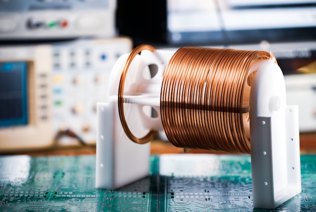 Close-up large and small coils with copper wire stand on a green microcircuit at a factory of classified military equipment. Super secret high-frequency components and equipment concept