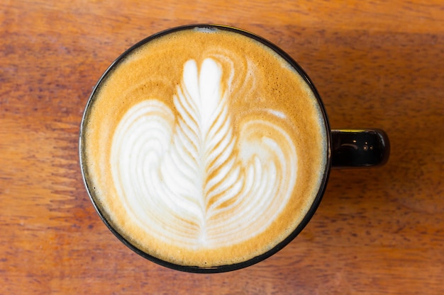 Foto close up latte caffè è in un bicchiere posto su un tavolo in caffetteria, uomo d'affari seduto a bere il caffè sulla scrivania, vista dall'alto caffè latte