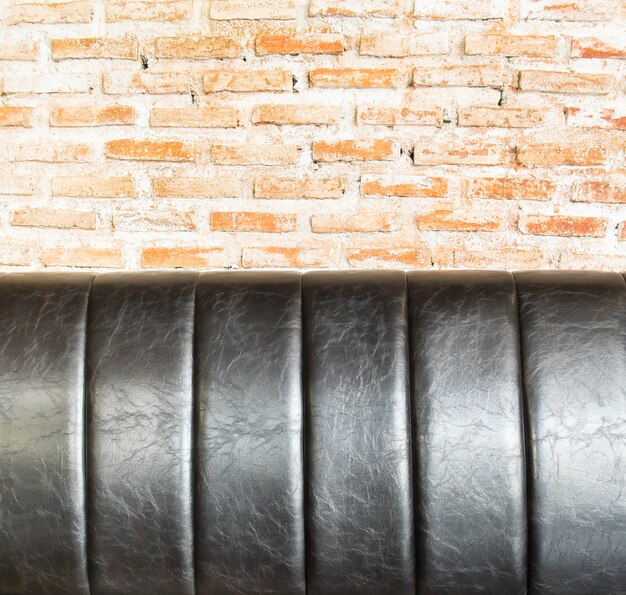 Close-up lederen sofa op oranje bakstenen muur