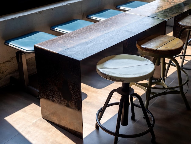 Close-up lege ronde draaibare houten stoelen stijlvol ijzer en hout lange tafel en rij wachtende stoel loft-stijl ingericht in café of restaurant in de buurt van het grote glazen raam met zonlicht van buitenaf