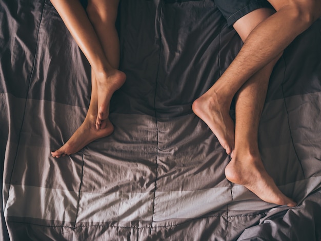 Close up of the legs of a couple on the bed.