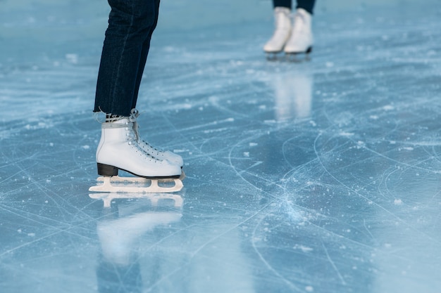 Close up of legs of ice skater on outdoor ice rink.