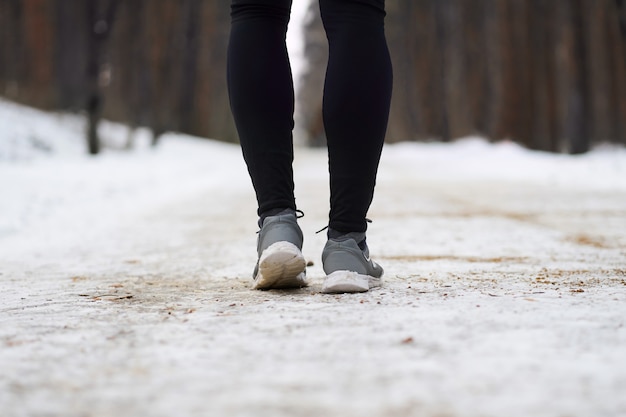 Close up legs of jogger during run in winter forest