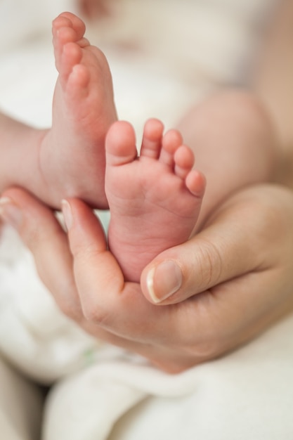 Close-up. The legs of the little baby in her mother's arms. Motherhood.