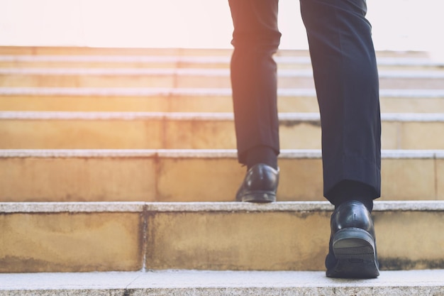 Photo close up legs shoes of young business man one person walking stepping going up the stairs in modern city, go up, success, grow up. with filter tones retro vintage warm effect. stairway