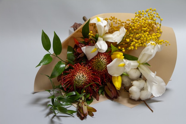 Close-up lenteboeket van ruscus, leucadendron, leucospermum, iris, katoen, mimosa-tak, tulp, selectieve aandacht