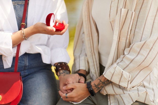 Photo close-up of lesbian holding ring and making proposal to her girlfriend outdoors