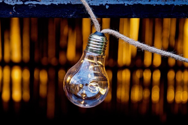 Photo close-up of light bulb hanging on rope