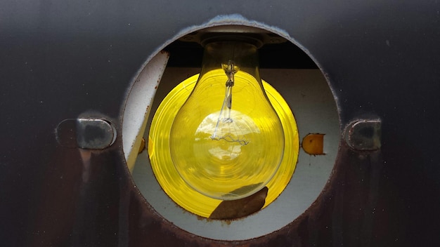 Photo close-up of light bulb seen through hole in metal