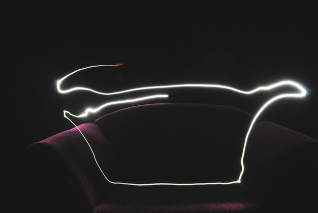 Photo close-up of light painting over sofa against black background