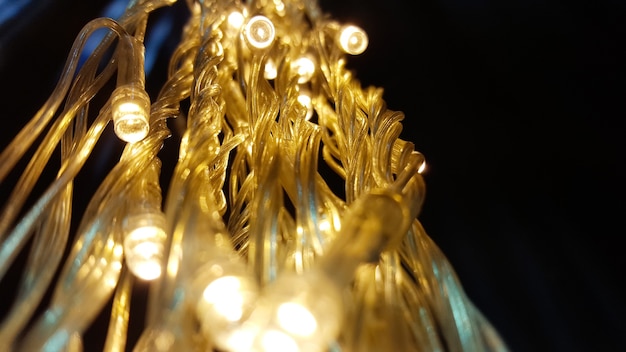 Close up lights of garland on the wall. Glowing electric garland on a black background.