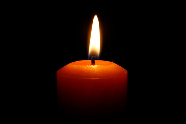 Close-up of lit candle against black background