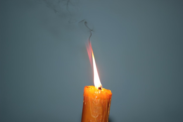 Photo close-up of lit candle against gray background