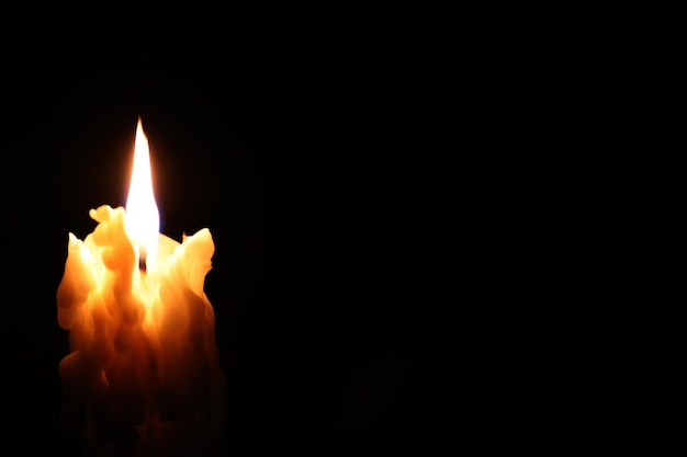 Foto close-up di una candela accesa in camera oscura