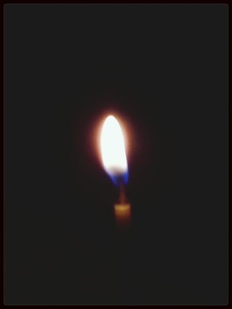 Photo close-up of lit candle in darkroom