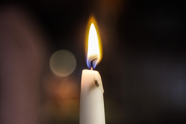 Close-up of lit candle in darkroom