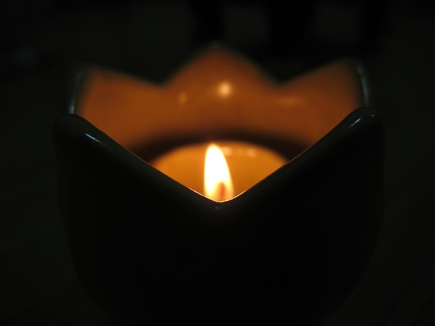 Photo close-up of lit candle in darkroom