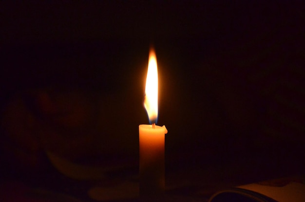 Close-up of lit candle in darkroom