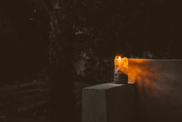 Close-up of lit candle on retaining wall at night