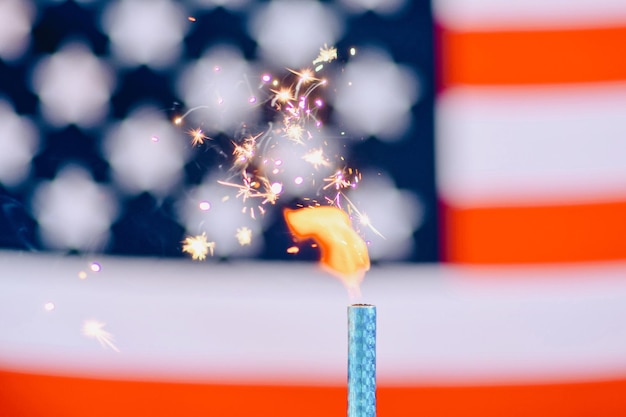 close-up of lit candle with sparks against american flag