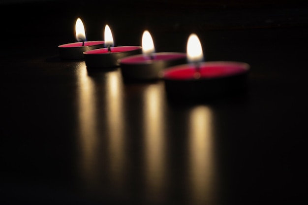 Photo close-up of lit candles in darkroom