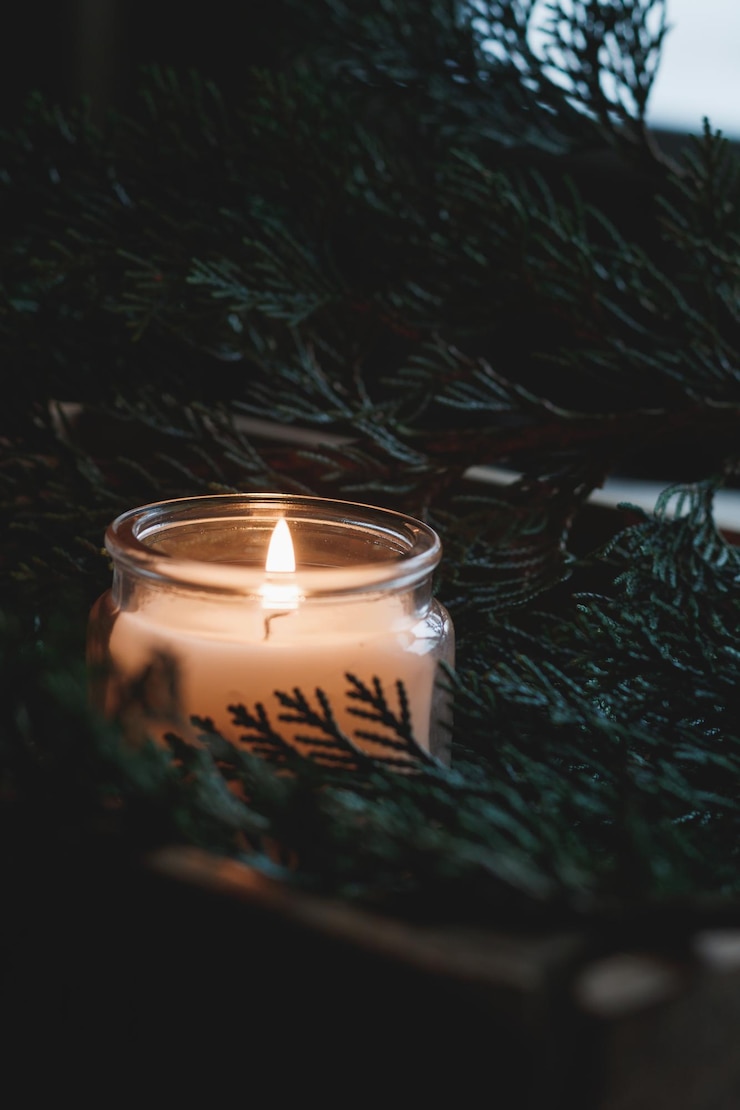Photo close-up of lit tea light candle amidst christmas tree