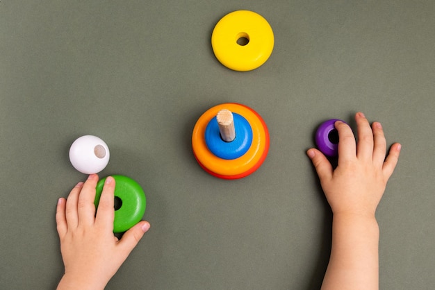 Close up of little baby wearing pajamas playing with wooden toy pyramid on green background  natural...