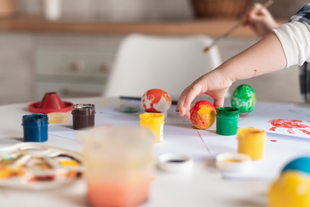 Photo close-up little boy painting eggs for easter