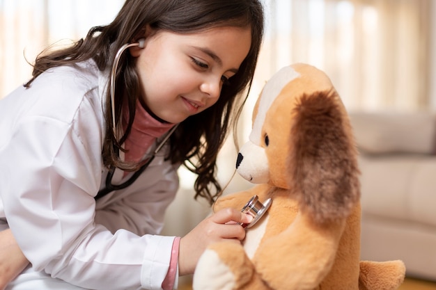 Primo piano di un bambino vestito come un medico auscultare il suo orsacchiotto