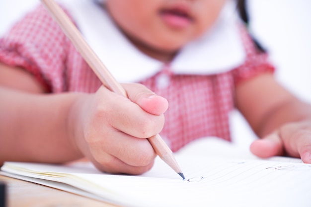 Foto chiuda sul piccolo bambino che impara scrivere sulla carta.